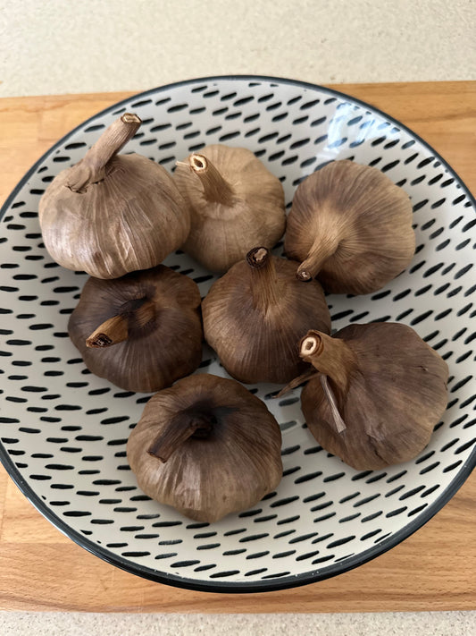 Bowl containing black garlic bulbs 